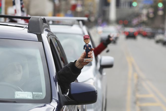 Protesters heading out of and into Niagara Square in Buffalo, New York, honk their horns as they head toward the Peace Bridge on February 12. One holds a bobblehead doll of former President Donald Trump out his window while stopped in traffic.