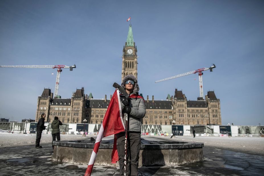 A protester stands with a Canadian flag in front of Parliament Hill in Ottawa.