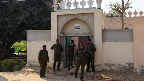 Police officers stand outside a mosque on Sunday, after authorities said the man was killed for allegedly burning pages of the Quran in Tulamba Village, Mian Channu, central Pakistan.