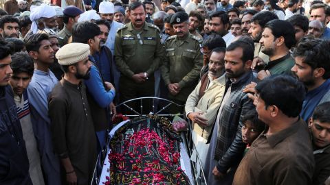 People stand beside the body of a man who, according to police, was lynched by a mob, in Tulamba Village, central Pakistan, on February 13, 2022.