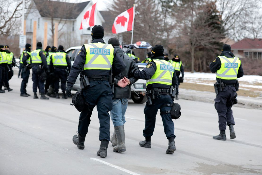 Police detain a man Sunday after protesters denouncing Covid-19 vaccine mandates blocked the entrance to the Ambassador Bridge in Windsor, Ontario.