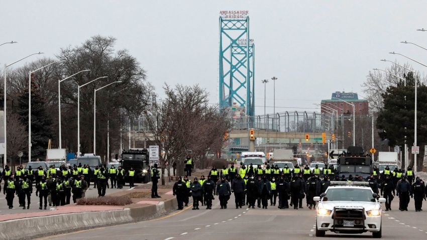 Police gather to clear protestors against Covid-19 vaccine mandates who blocked the entrance to the Ambassador Bridge in Windsor, Ontario, Canada, on February 13, 2022. - Canadian police resumed operations Sunday to clear a key US border bridge occupied by trucker-led demonstrators angry over Covid-19 restrictions, as authorities began making arrests in their bid to quell a movement that has also paralyzed downtown Ottawa. (Photo by JEFF KOWALSKY / AFP) (Photo by JEFF KOWALSKY/AFP via Getty Images)