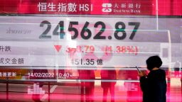 A woman walks past a bank's electronic board showing the Hong Kong share index at Hong Kong Stock Exchange Monday, Feb. 14, 2022. Asian stock markets fell Monday and oil prices rose amid concern about a possible Russian invasion of Ukraine. (AP Photo/Vincent Yu)