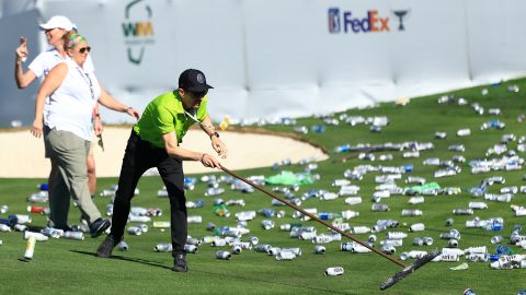 Groundskeepers pick up bottles thrown from the stands on the 16th hole after a hole-in-one by Sam Ryder.