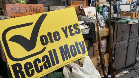 Two rifles are propped up near a "Recall Moty" sign in Clenenden's barber shop.