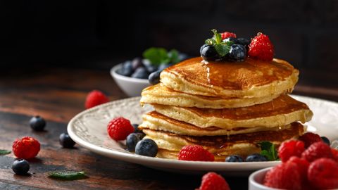 A stack of American pancakes with fresh blueberry, raspberries and honey. 