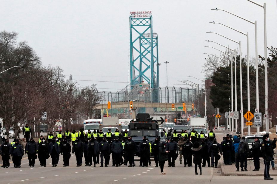 Police gather to clear protesters who blocked the entrance to the Ambassador Bridge in Windsor, Ontario, on Sunday, February 13. The Ambassador Bridge, North America's busiest land border crossing, reopened Sunday.