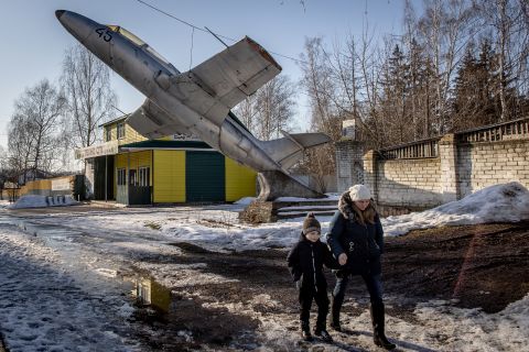A woman and child walk underneath a military monument in Senkivka, Ukraine, on February 14. It's on the outskirts of the Three Sisters border crossing between Ukraine, Russia and Belarus.