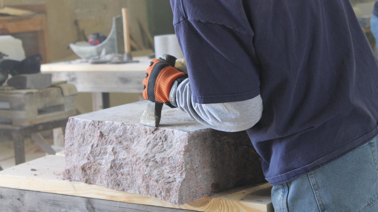 A stone cutter in Elberton, Georgia, uses a hammer and chisel to create the rough edges of a monument.