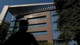 A man is silhouetted as he talks on his mobile phone while standing in front of the Google India office building in Hyderabad on January 28, 2022. 