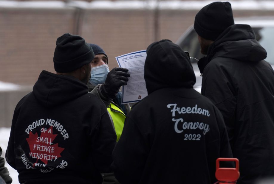 A police officer holds up <a href="https://www.cnn.com/2022/02/16/americas/canada-truckers-protest-wednesday/index.html" target="_blank">a flyer that was being distributed to protesters</a> in Ottawa on February 16. Police said they may arrest anyone blocking streets or assisting someone who is doing so.