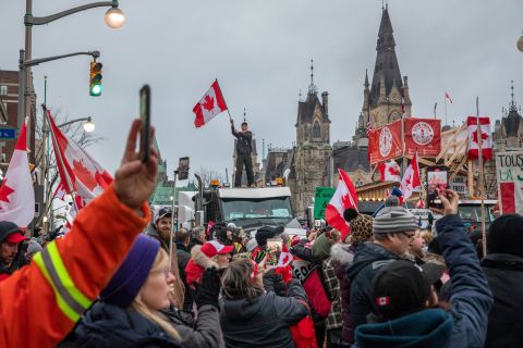 A demonstrator stands atop a truck holding a Canadian flag during a protest near the Canadian Parliament in Ottawa on Friday, February 11. <a href="http://www.cnn.com/2022/02/11/world/gallery/canadian-trucker-protest/index.html" target="_blank">A massive protest against Covid-19 mandates</a> has been growing for weeks, crippling downtown Ottawa and a few US border crossings. Thousands of truckers have been participating in the so-called <a href="https://www.cnn.com/2022/02/07/americas/canada-covid-protest-explainer/index.html" target="_blank">Freedom Convoy,</a> fighting a mandate that requires all Canadian truckers crossing the US-Canadian border to be fully vaccinated or quarantine in their homes for two weeks when they return.