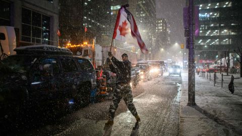 Snow falls around a demonstrator waving a flag  outside  parliament in Ottawa on February 17, 2022.