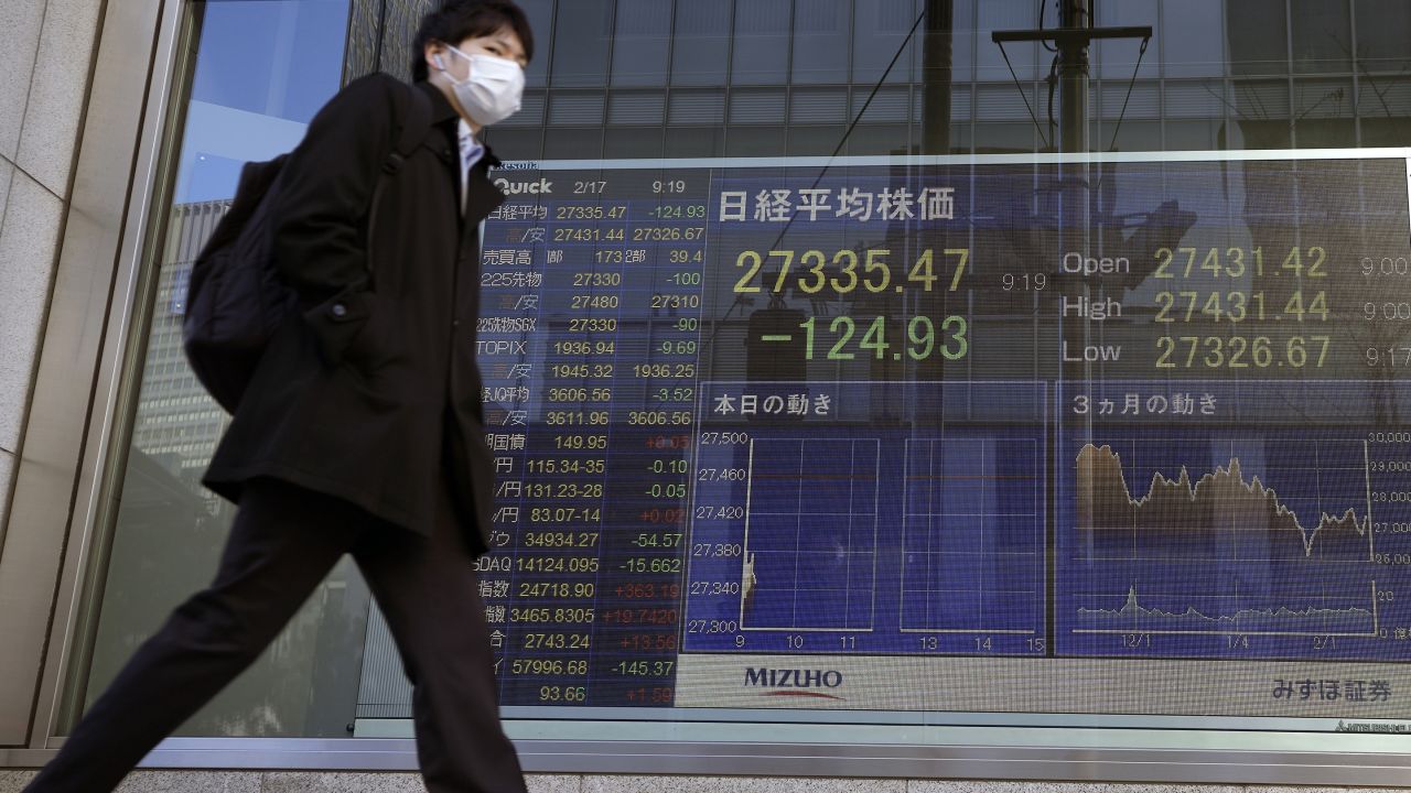 A pedestrian moves past a monitor showing Japan's Nikkei 225 index, at a securities firm in Tokyo, Thursday, Feb. 17, 2022. Asian stock markets followed Wall Street higher Thursday after Federal Reserve policymakers indicated they are leaning toward more decisive action on inflation but set no firm targets. (AP Photo/Shuji Kajiyama)