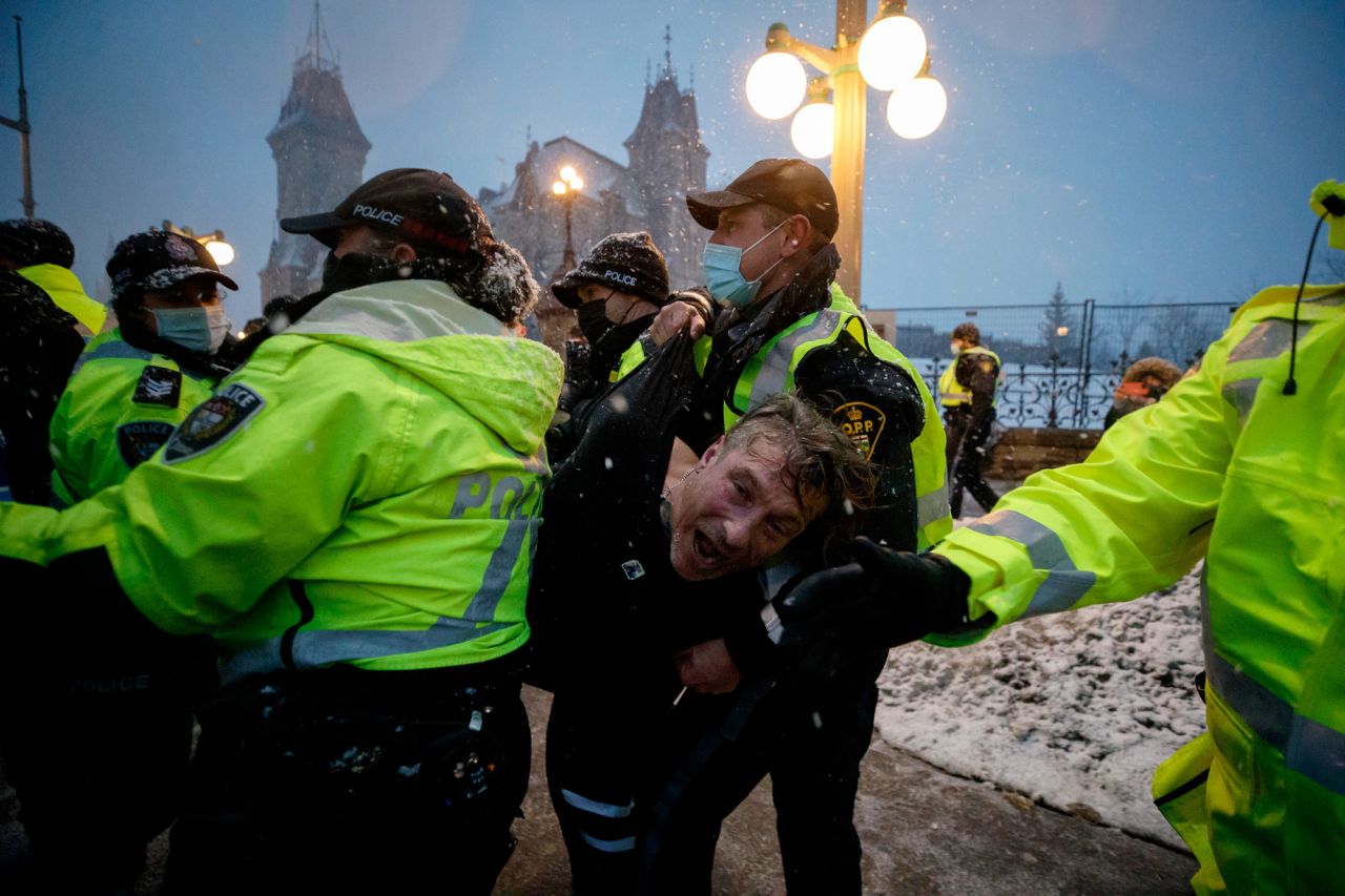 A man is detained by police as protesters and supporters gather in downtown Ottawa on Thursday, February 17.
