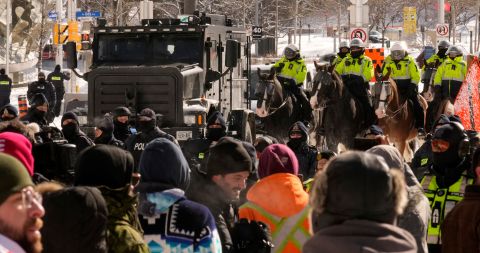 Police gather near the site of the trucker blockade on February 18. Police began arresting protesters and towing away trucks Friday to clear streets that have been blocked for weeks.