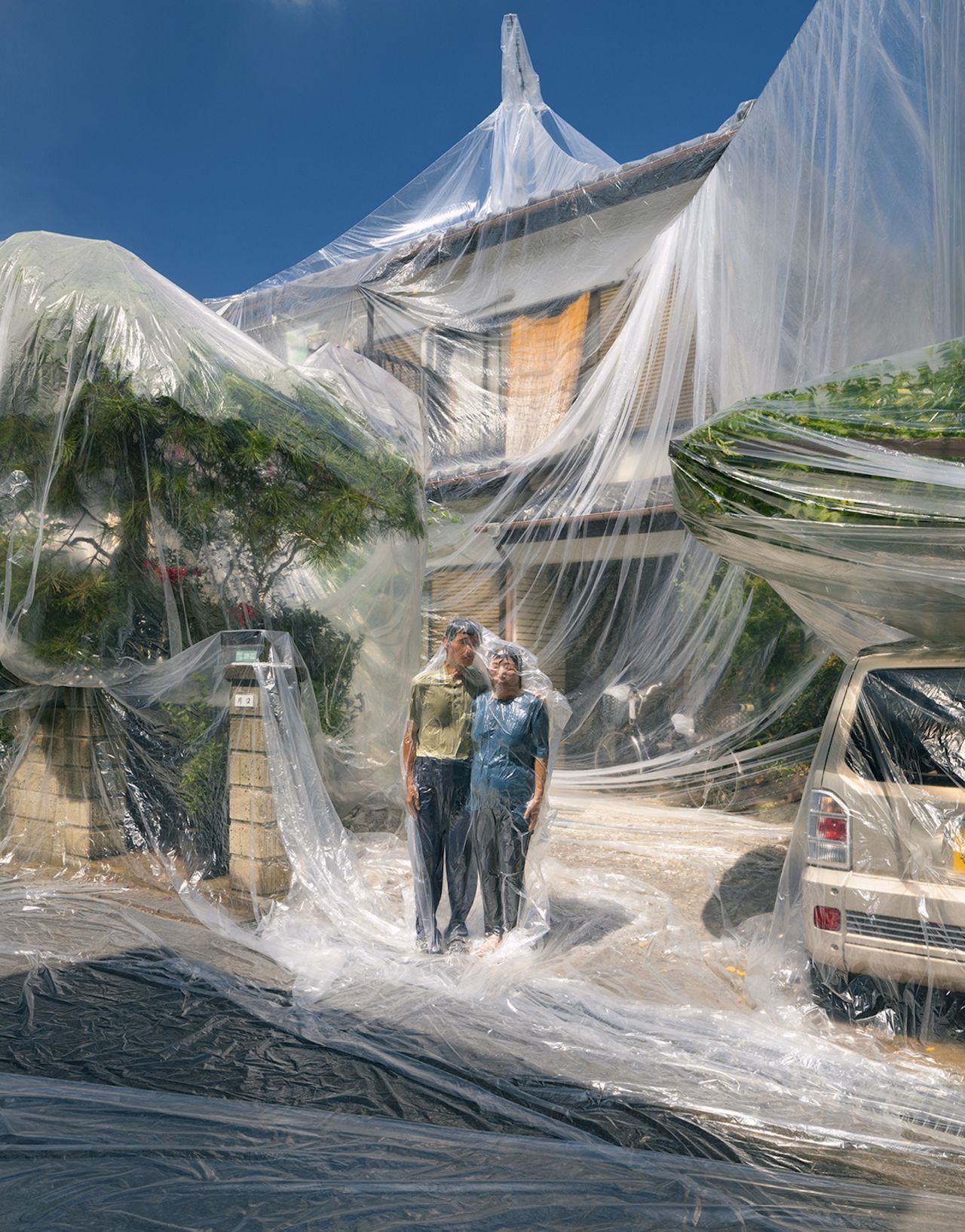 Kawaguchi custom-made huge plastic sheets to encase entire homes, including trees and vehicles.