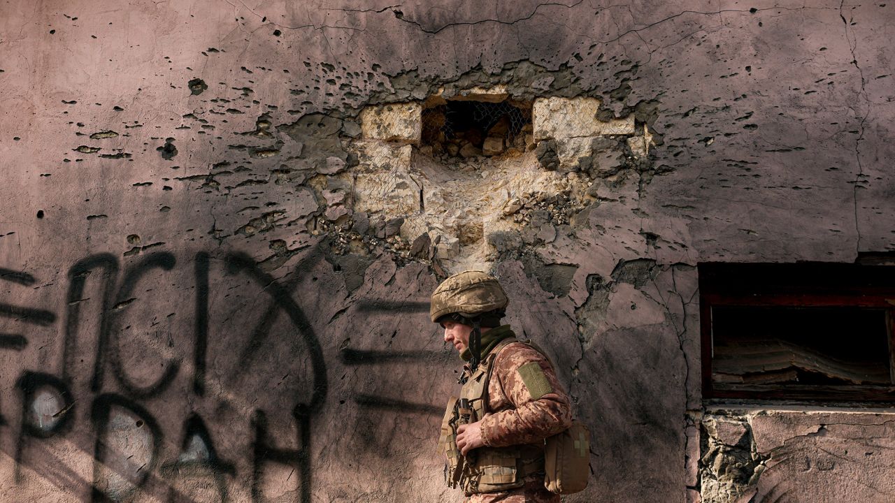 A Ukrainian serviceman walks by a building which was hit by a large caliber mortar shell in the frontline village of Krymske, Luhansk region, in eastern Ukraine, Saturday, Feb. 19, 2022. Ukrainian President Volodymyr Zelenskyy, facing a sharp spike in violence in and around territory held by Russia-backed rebels and increasingly dire warnings that Russia plans to invade, on Saturday called for Russian President Vladimir Putin to meet him and seek resolution to the crisis. (AP Photo/Vadim Ghirda)