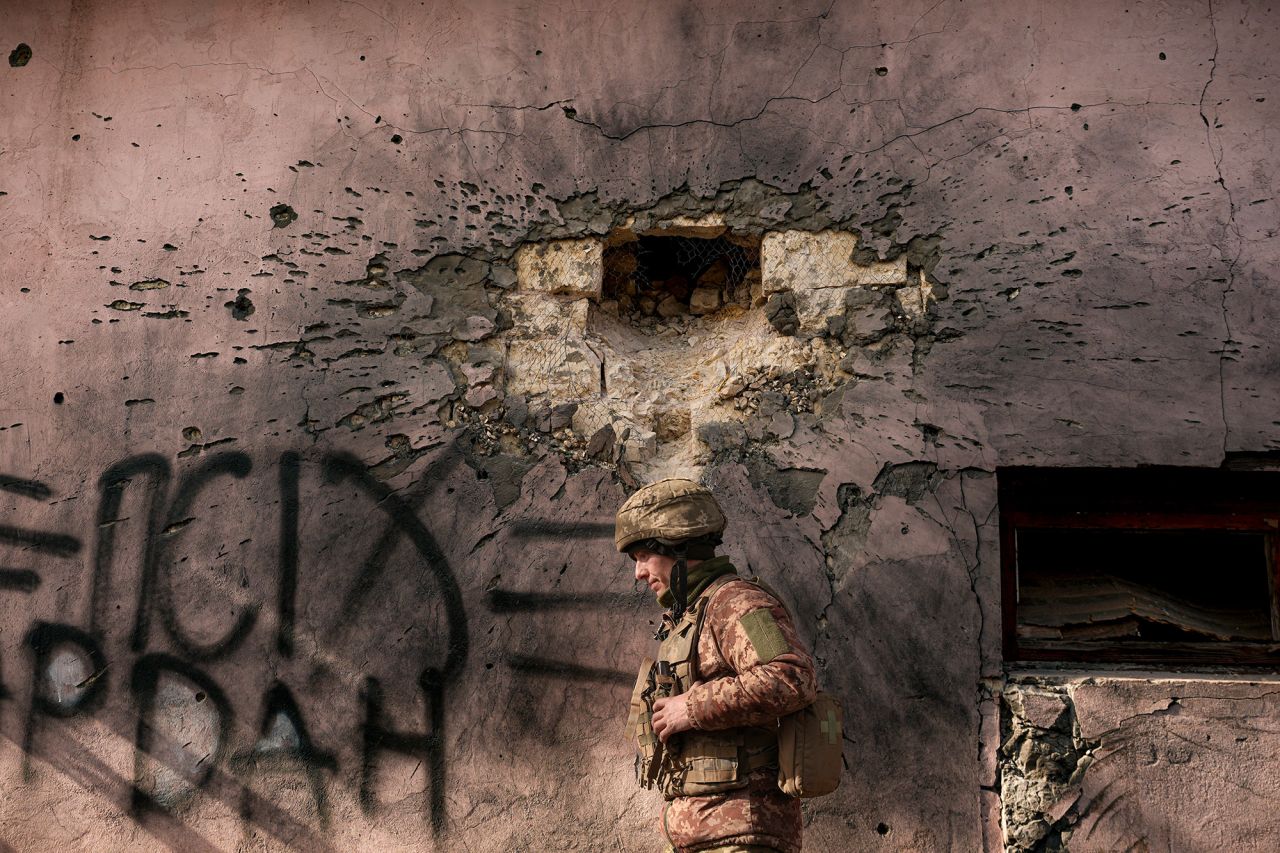 A Ukrainian service member walks by a building on February 19 that was hit by mortar fire in the front-line village of Krymske, Ukraine.