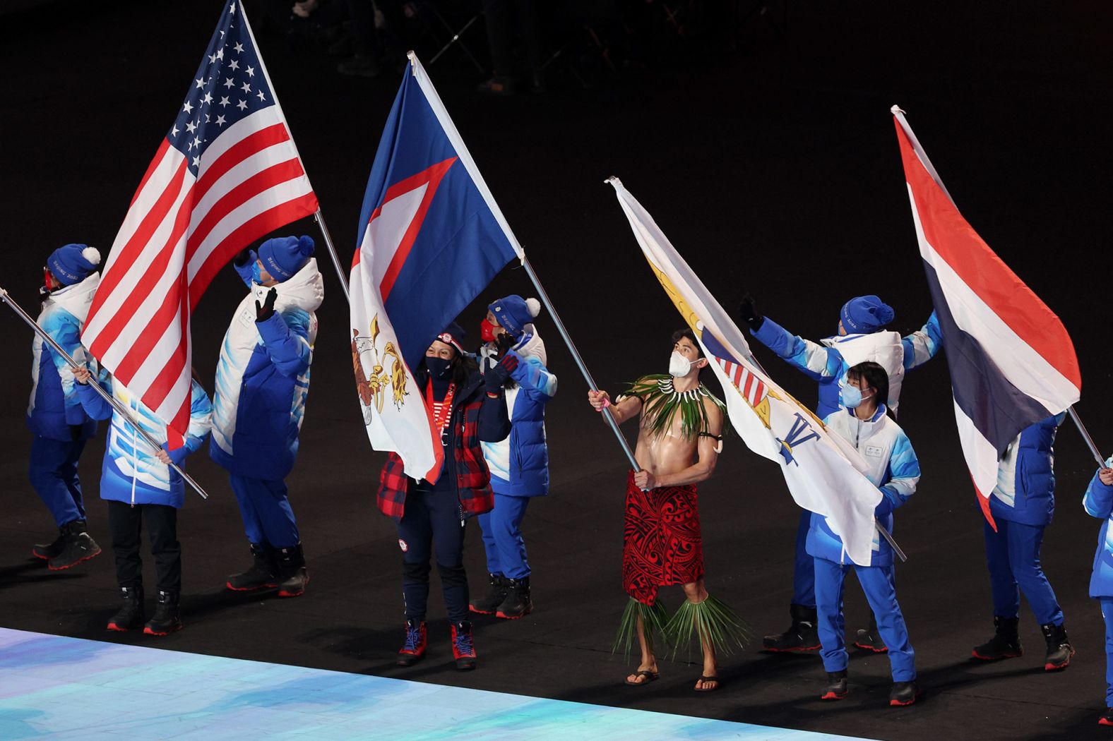 Flagbearers take part in the ceremony. Holding the American flag is bobsledder Elana Meyers Taylor, <a href="index.php?page=&url=https%3A%2F%2Fwww.cnn.com%2F2022%2F02%2F19%2Fsport%2Felana-meyers-taylor-most-decorated-black-athlete-winter-olympics-history-spt-intl%2Findex.html" target="_blank">the most decorated Black athlete in Winter Olympics history.</a> Going shirtless is Nathan Crumpton, <a href="index.php?page=&url=https%3A%2F%2Fwww.cnn.com%2Fworld%2Flive-news%2Fbeijing-winter-olympics-02-20-22-spt%2Fh_5a347e24668081fc91dc0f1f54011cef" target="_blank">American Samoa's sole athlete in these Olympics.</a>