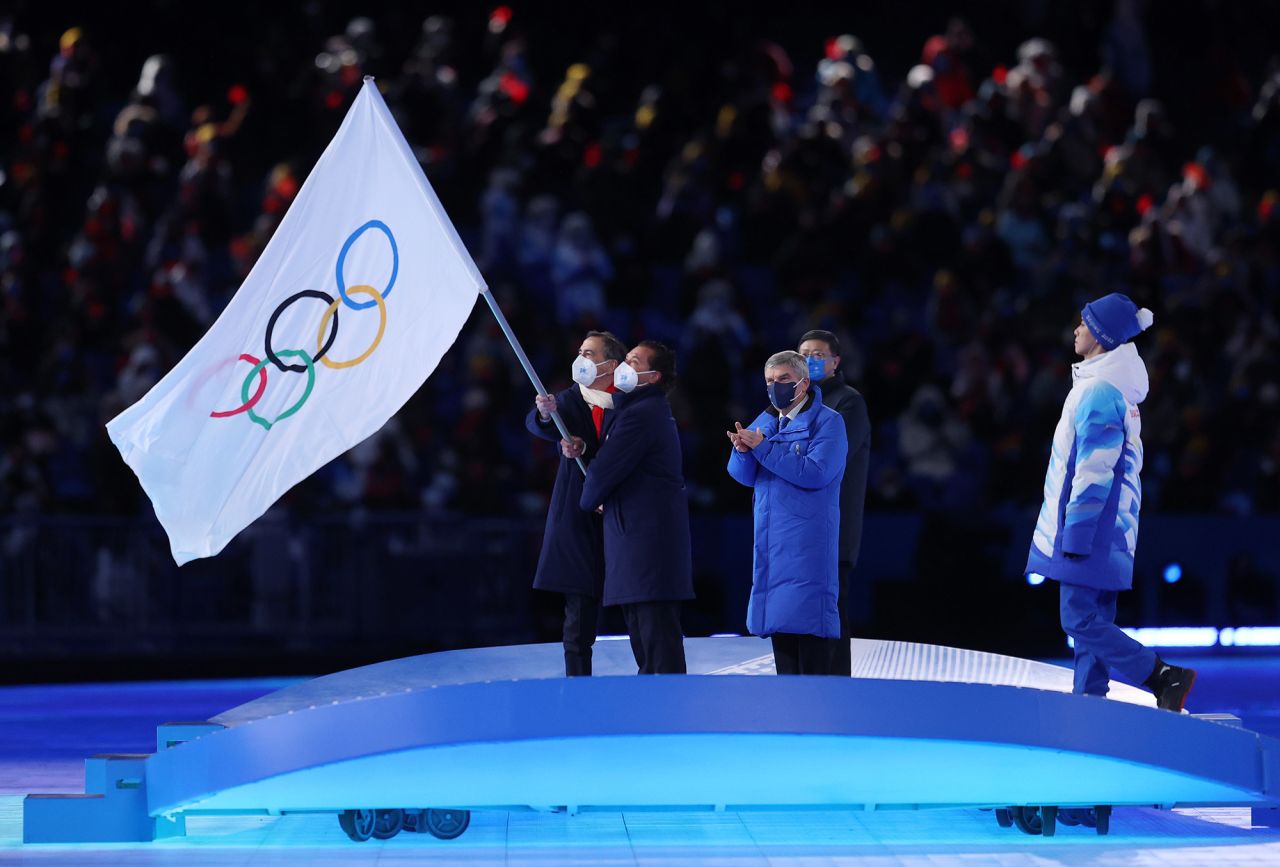 Guiseppe Sala and Gianpietro Ghedina — the mayors of the Italian cities of Milan and Cortina d'Ampezzo — wave the Olympic flag during the ceremony. Those cities will host the Winter Games in 2026.
