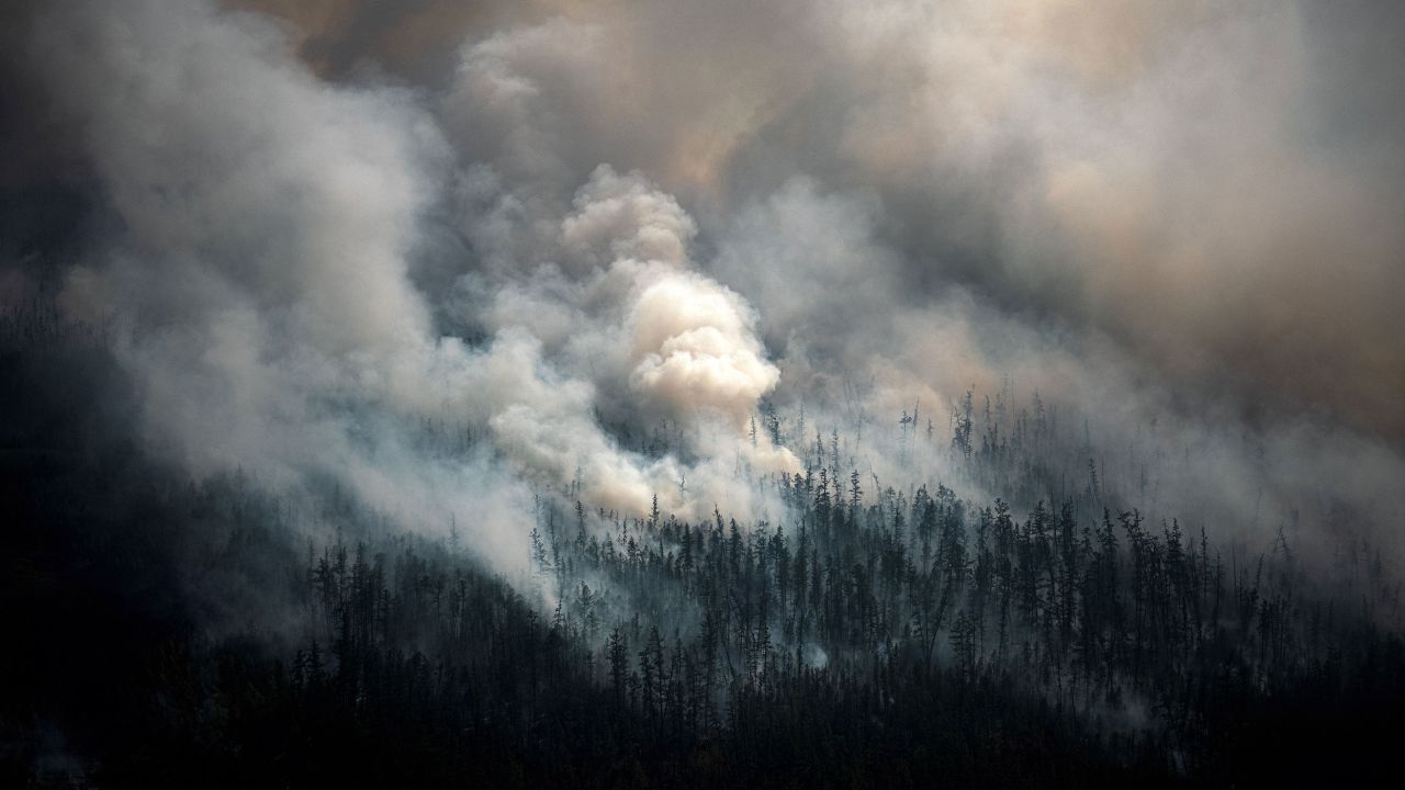 Smoke rises from a forest fire outside the village of Berdigestyakh, in the republic of Sakha, Siberia, in July 2021. UN researchers are encouraging policymakers to reframe how they think about wildfires, switching "from reactive to proactive."