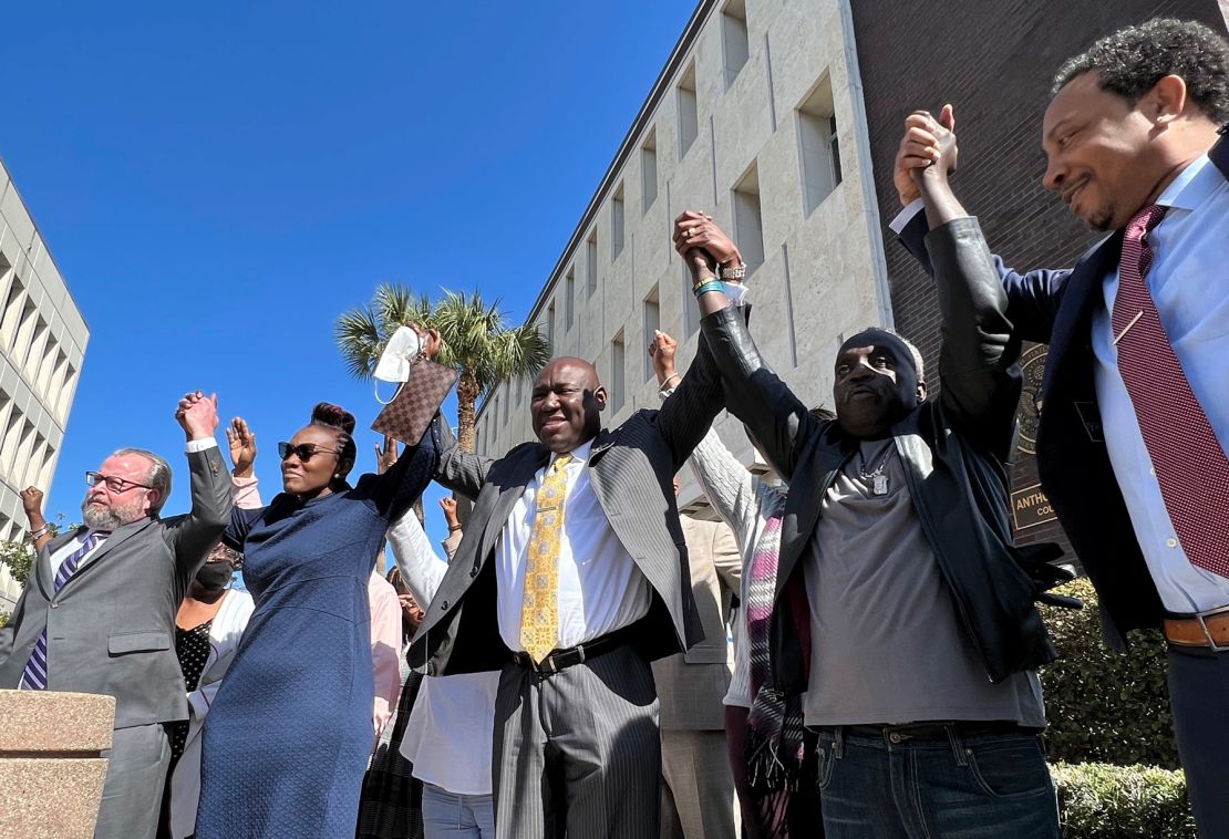 The family of Ahmaud Arbery and attorneys raise their arms in victory Tuesday outside the federal courthouse in Brunswick, Georgia, after all three men involved in his killing were found guilty of hate crimes.