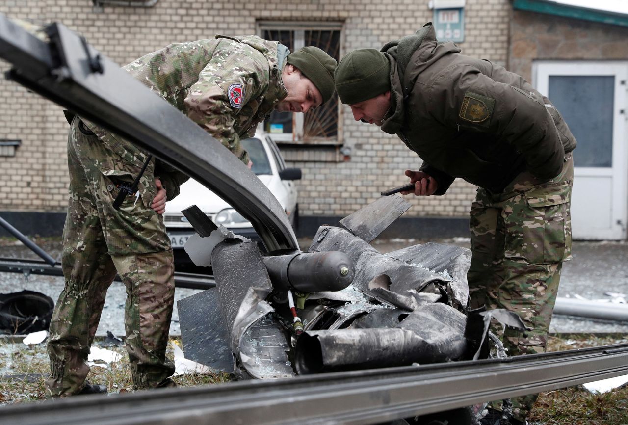 Police officers inspect the remains of a missile that landed in Kyiv on February 24.