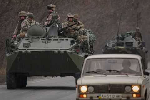 Ukrainian service members sit atop armored vehicles driving in eastern Ukraine's Donetsk region on February 24.