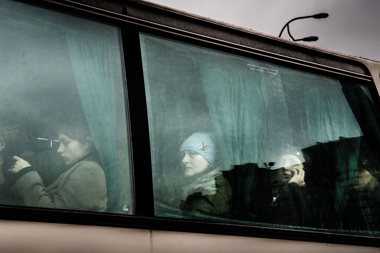 People wait after boarding a bus to leave Kyiv on February 24.