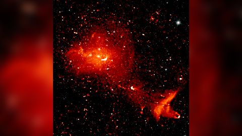 A composite radio (red) and infrared (white) image depicts the Coma cluster, which is over 300 million light-years from Earth and consists of over 1,000 individual galaxies. The radio image shows radiation from highly energetic particles that pervade the space between the galaxies. 