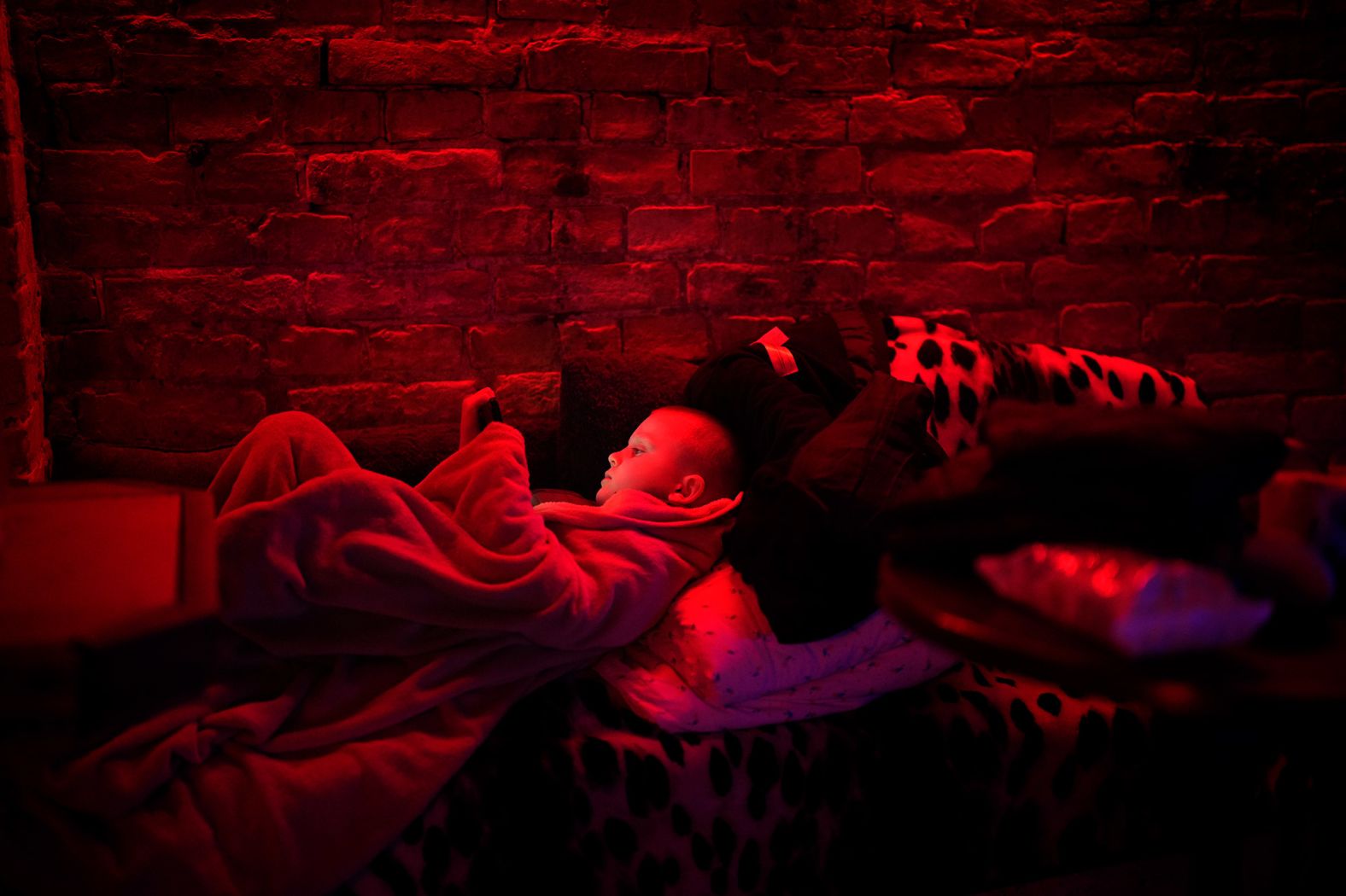 A boy plays with his tablet in a public basement used as a bomb shelter in Kyiv on February 24.