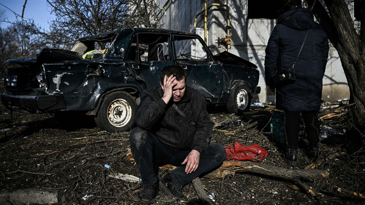 A man sits outside his destroyed building after bombings on the eastern Ukraine town of Chuguiv on February 24, 2022.