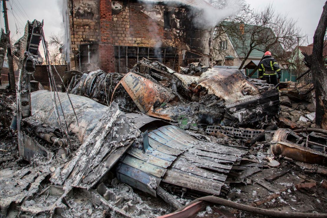 A Ukrainian firefighter walks between fragments of a downed aircraft in Kyiv, Ukraine, Friday, February 25, 2022. It was unclear what aircraft crashed and what brought it down.