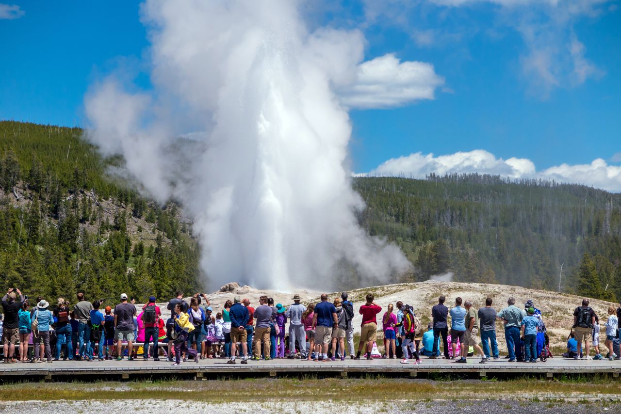 <strong>Old Faithful:</strong> Tourists watch Old Faithful, the park's most famous feature, eject its regular hot spray. The geyser has lengthened the time between eruptions by about 30 minutes in the past 30 years, the National Park Service says.