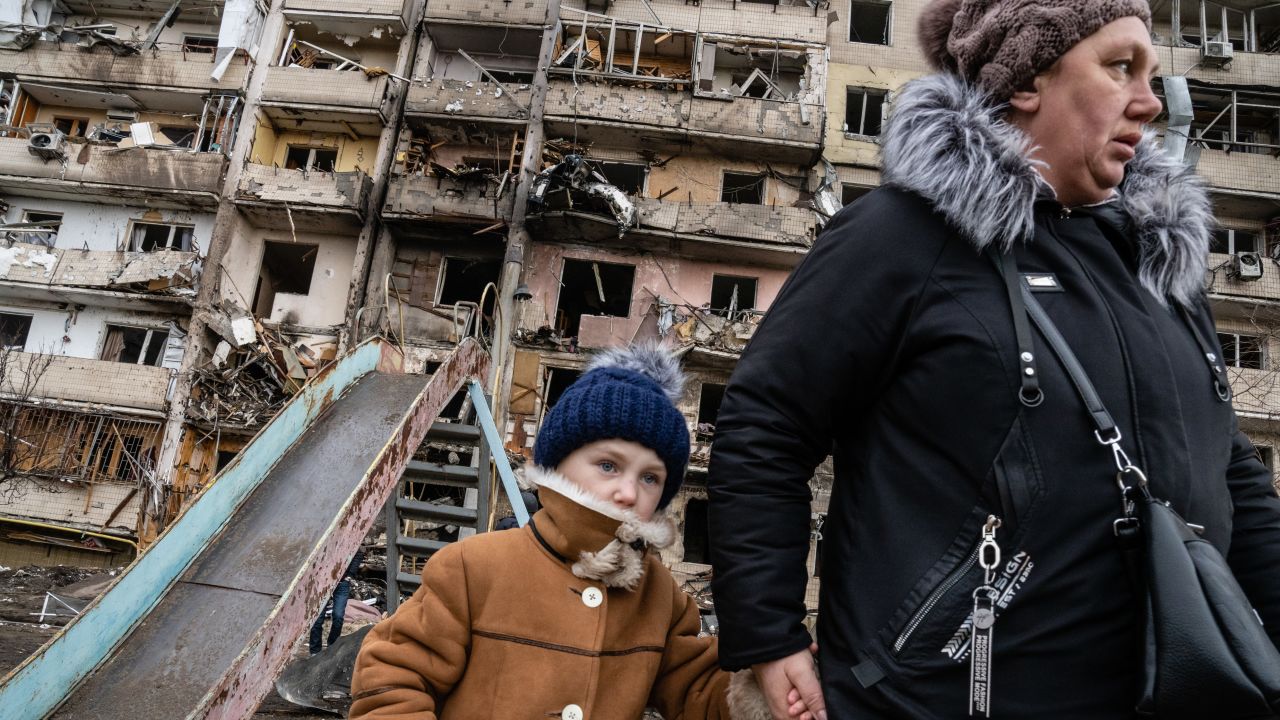 Onlookers survey the damage at a residential building that was hit in an alleged Russian airstrike in the Ukrainian capital Kyiv on February 25.