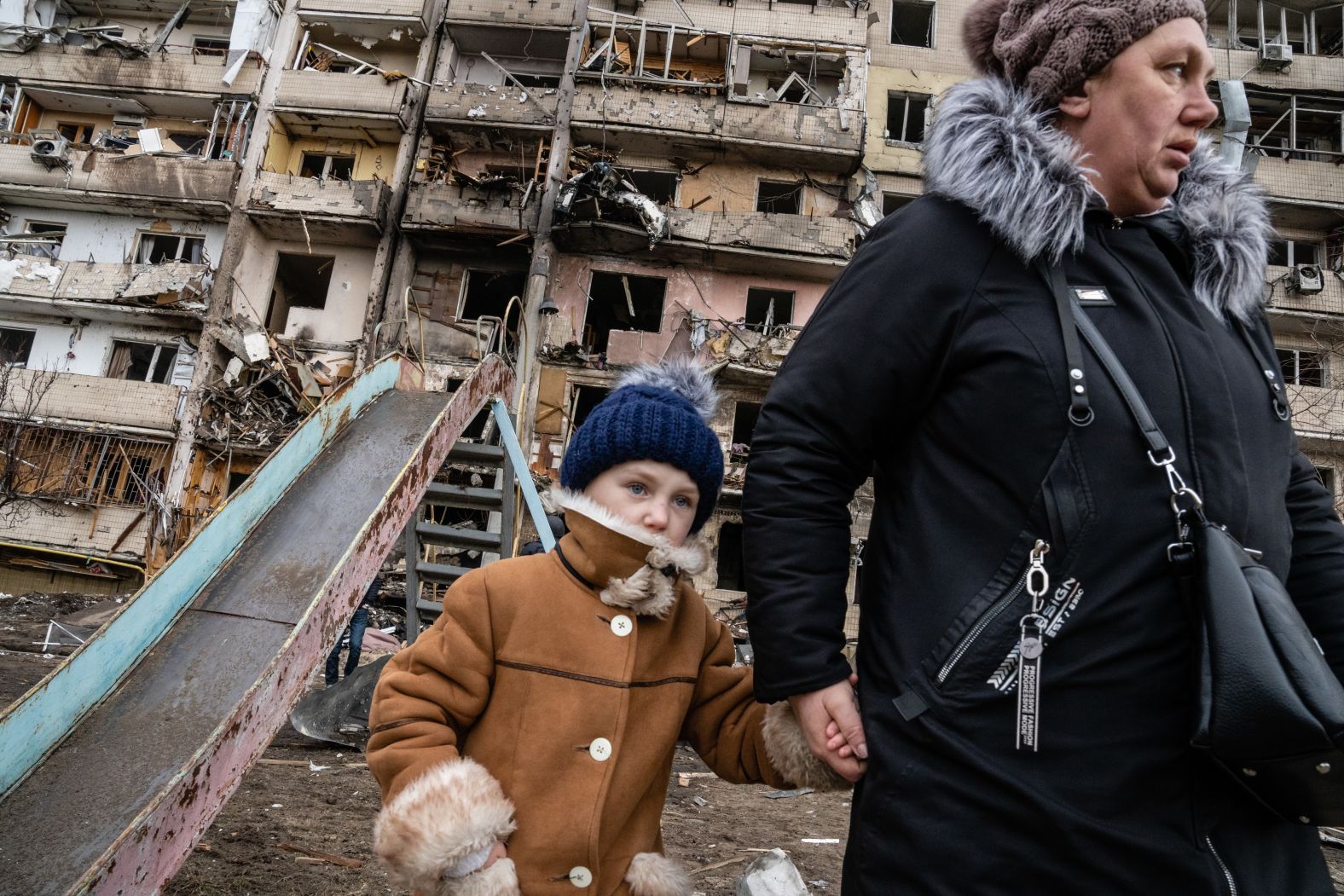 People walk past a residential building that was hit in an alleged Russian airstrike in Kyiv, Ukraine, on February 25.
