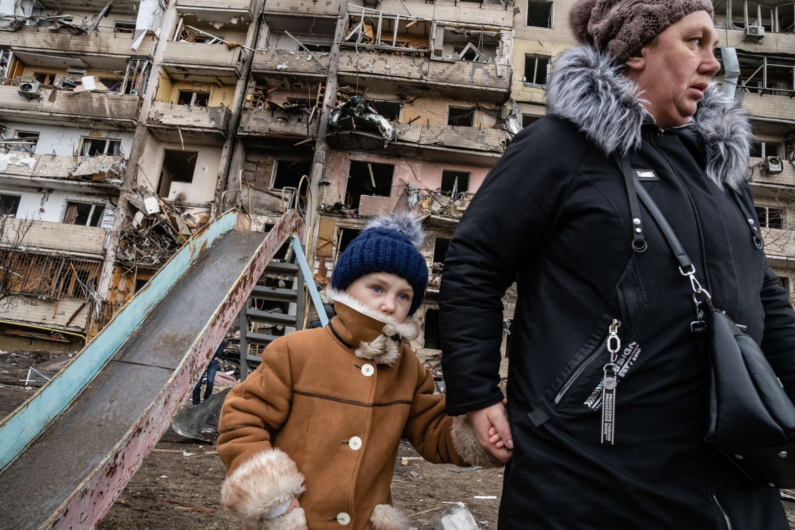 People walk past a residential building in Kyiv that was hit in an alleged Russian airstrike on February 25.