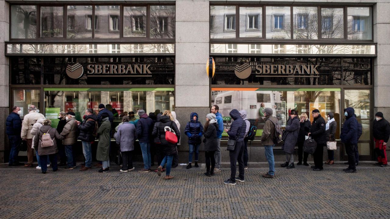 People queue outside a branch of the Russian state-owned bank Sberbank to withdraw their savings in Prague, Czech Republic, on Friday, February 25, 2022, after sanctions against the bank were announced.