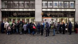 People queue outside a branch of Russian state-owned bank Sberbank to withdraw their savings and close their accounts in Prague on February 25, 2022, before Sberbank will close all its branches in the Czech Republic later in the day. - US President Biden was the first to announce sanctions, hours after Russian President Putin declared a 