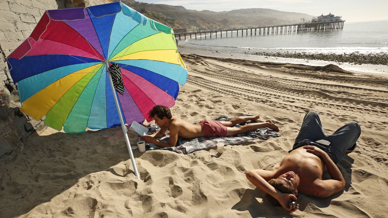 Matthew Bautista, 24, left, and friend Bobby Kraemer, 27, right, spend the morning at Surfrider Beach in Malibu as a spate of unseasonably warm weather continues on April 30, 2021, at Surfrider Beach in Malibu, California.