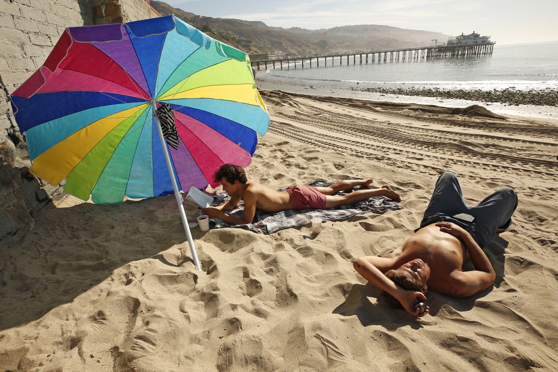 Matthew Bautista, 24, left, and friend Bobby Kraemer, 27, right, spend the morning at Surfrider Beach in Malibu as a spate of unseasonably warm weather continues on April 30, 2021, at Surfrider Beach in Malibu, California.