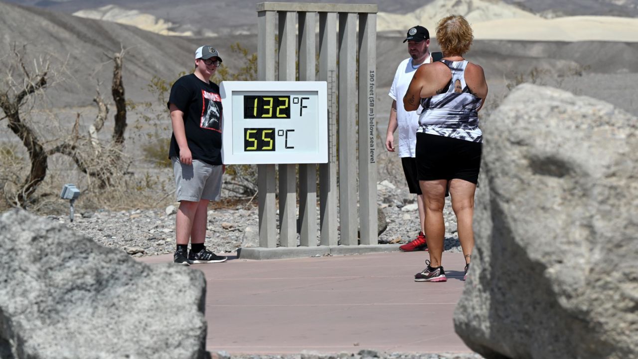 People pose by an unofficial thermometer reading 132 degrees Fahrenheit/55 degrees Celsius at Furnace Creek Visitor Center on July 11, 2021 in Death Valley National Park, California.
