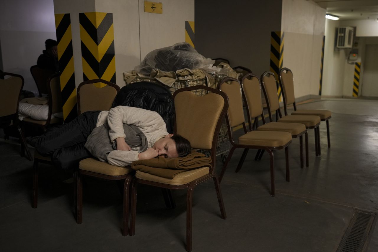 A woman sleeps on chairs February 27 in the underground parking lot of a Kyiv hotel that has been turned into a bomb shelter.  Zelensky says Russia waging war so Putin can stay in power &#8216;until the end of his life&#8217; w 1280