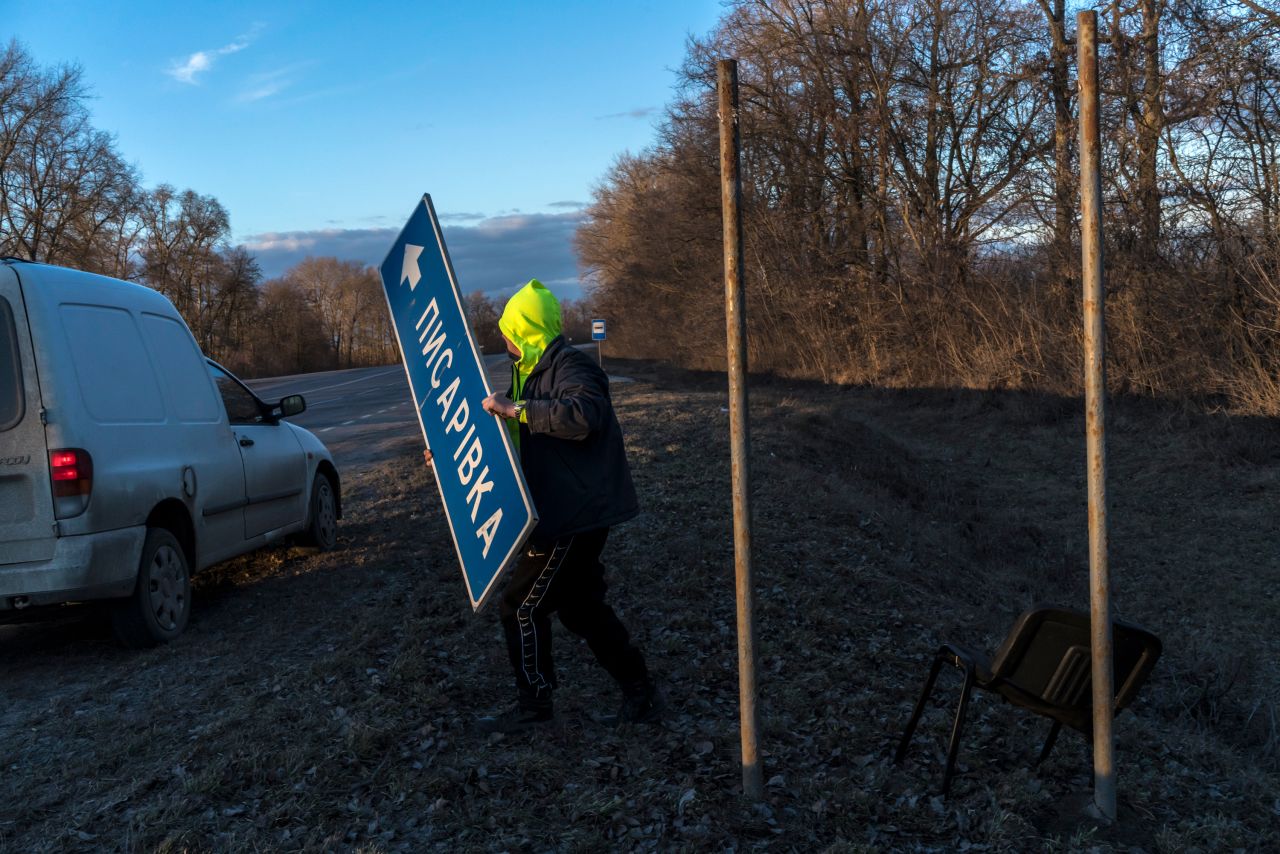 Following a national directive to help complicate the invading Russian Army's attempts to navigate, a road worker removes signs near Pisarivka, Ukraine, on February 26.