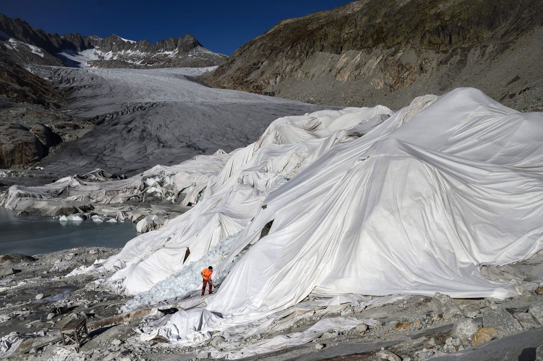 A man works in the Swiss Alps at the Rhone Glacier in October 2021, which is partially covered with insulating foam to prevent it from melting due to global warming.