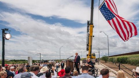People listen to Texas Gov. Greg Abbott's address, during a tour to an unfinished section of the border wall with former President Donald Trump on June 30, 2021 in Pharr, Texas.
