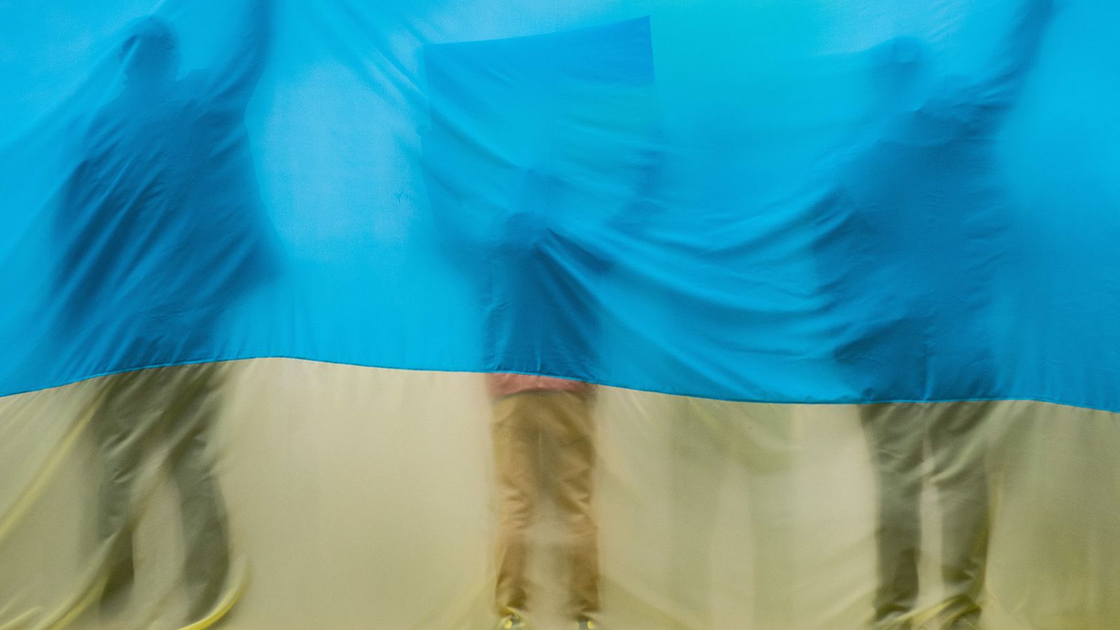 Silhouettes are seen through a Ukrainian flag during a demonstration in Madrid on February 27.