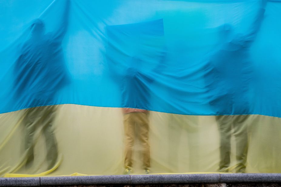 Silhouettes are seen through a Ukrainian flag during a demonstration in Madrid on February 27.