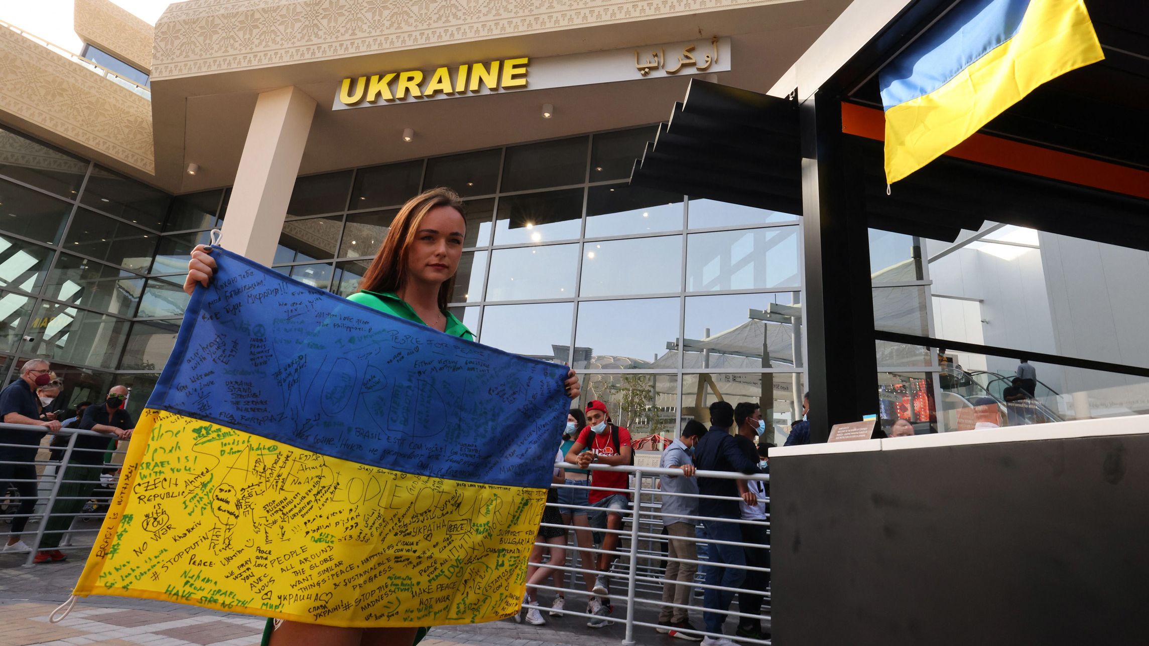 A woman poses for a picture with a signed Ukranian flag at the Ukraine pavillion at Expo 2020 in Dubai, on February 27.